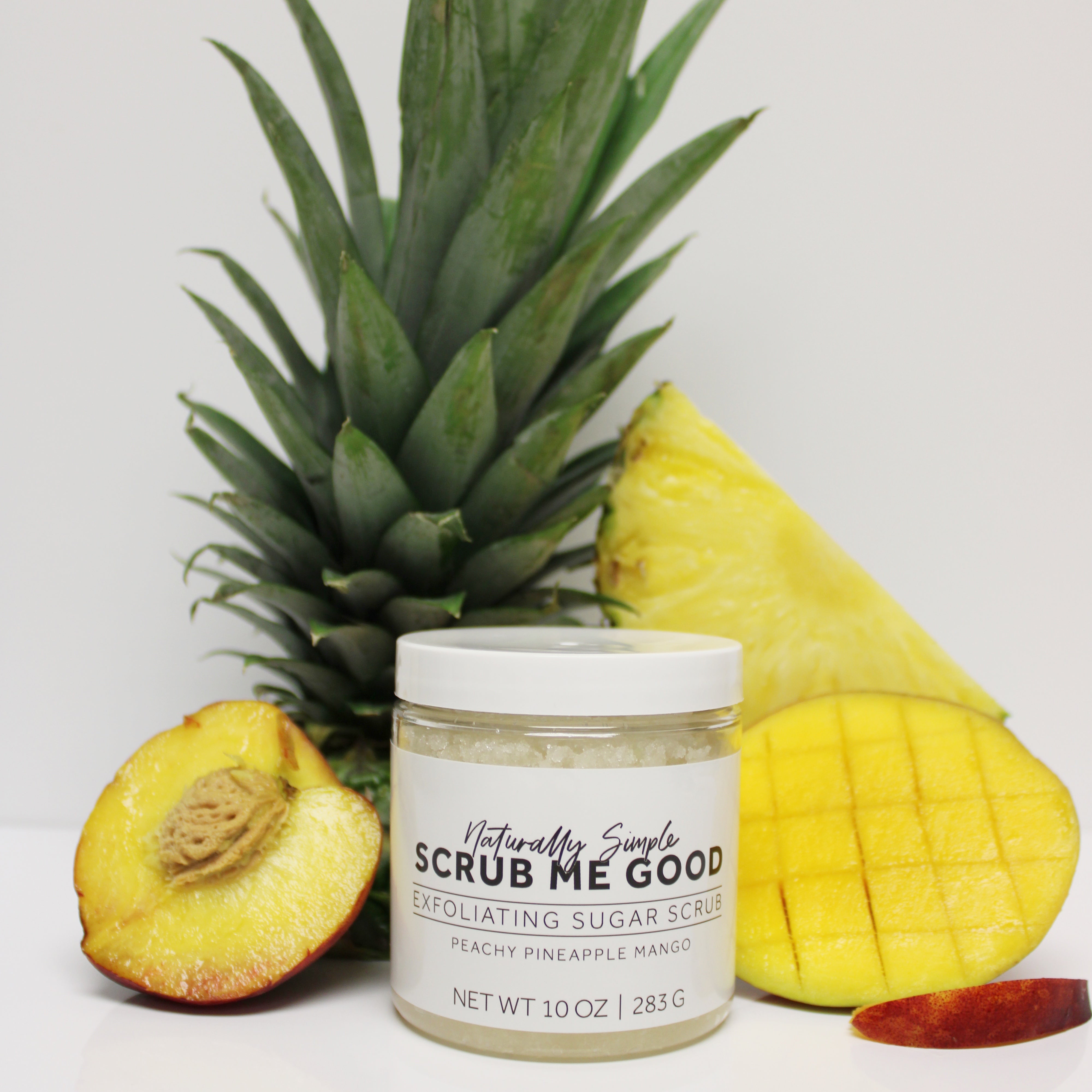 Sugar Scrub surrounded by fruit, pineapple, peach and mango
