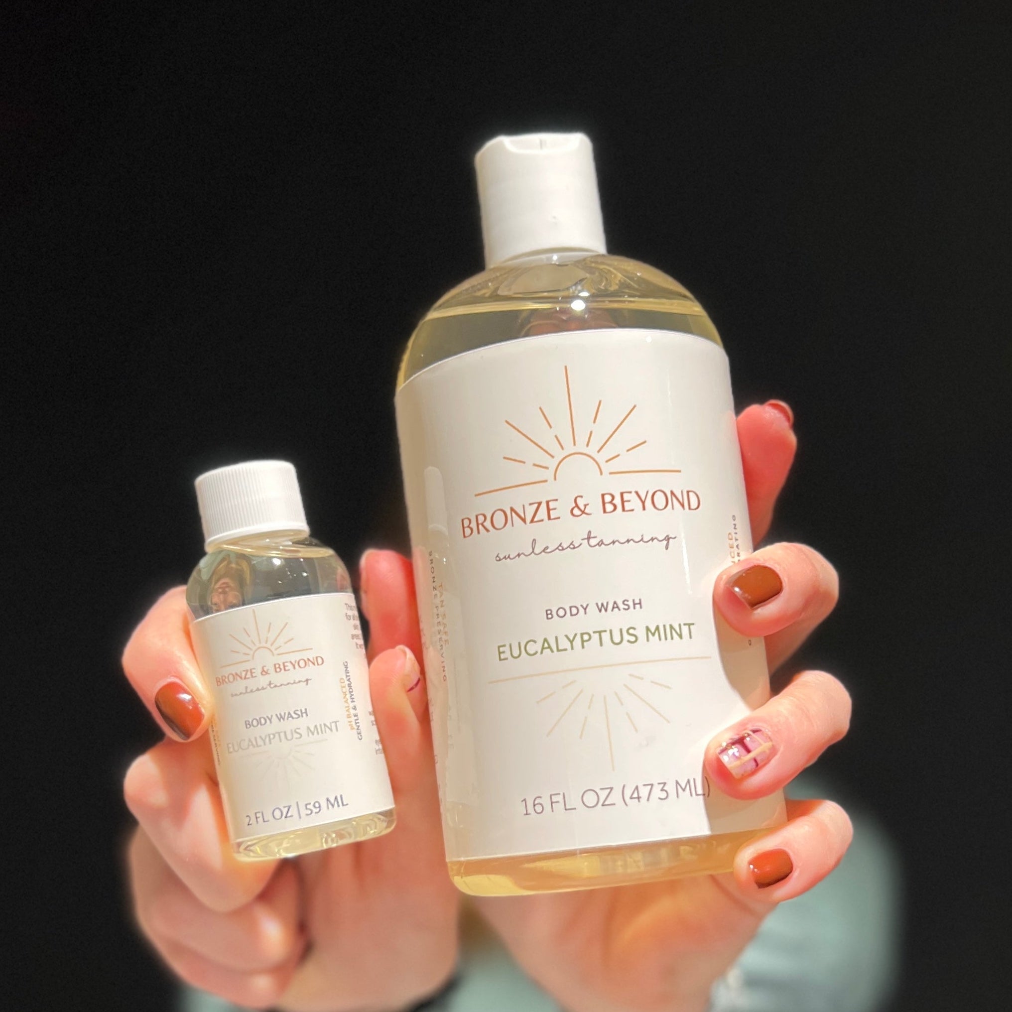 Two bottles of 'Bronze & Beyond' body wash held against a black background