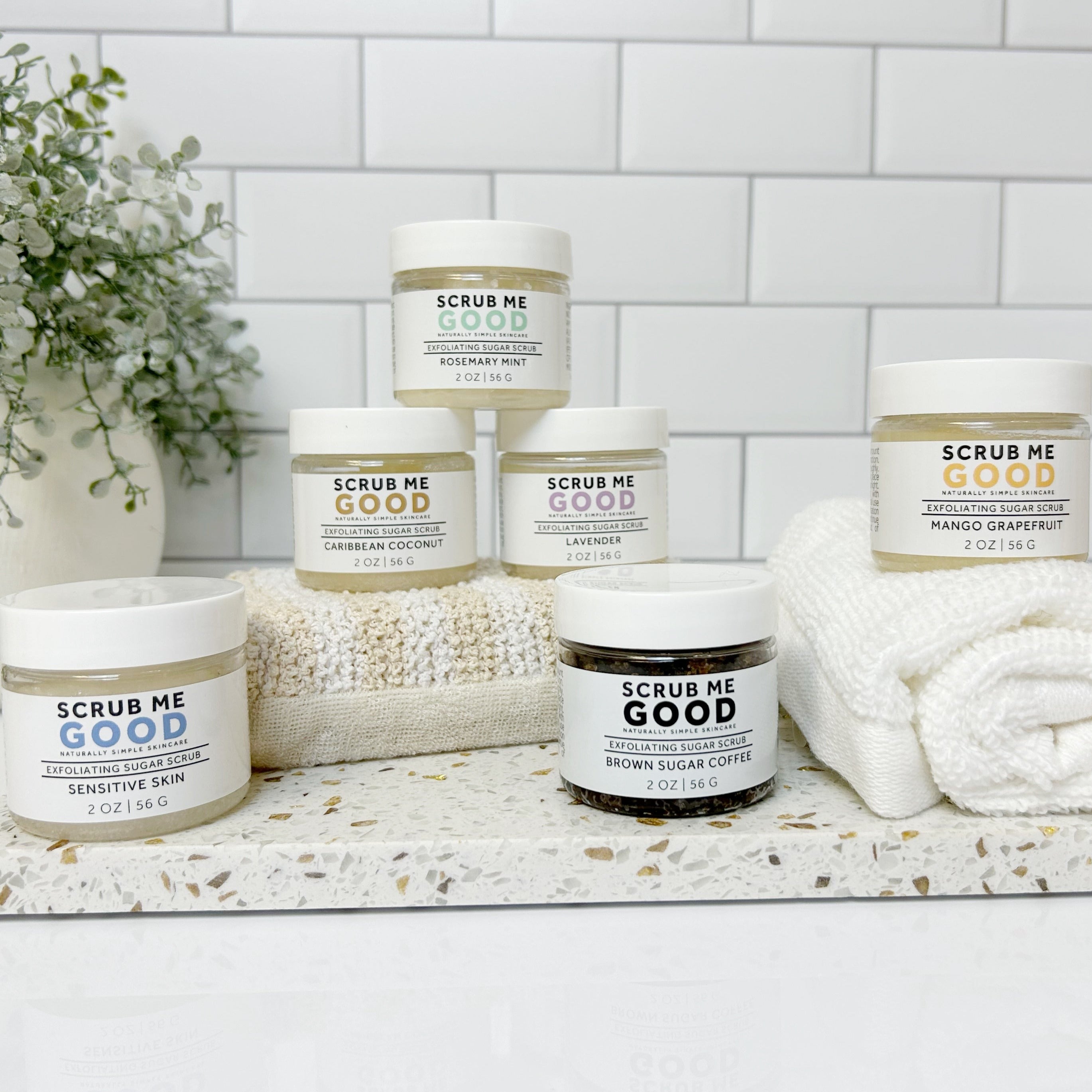 Convenient exfoliating scrub for vacations and on-the-go skincare. stacked jars on towels and sponges