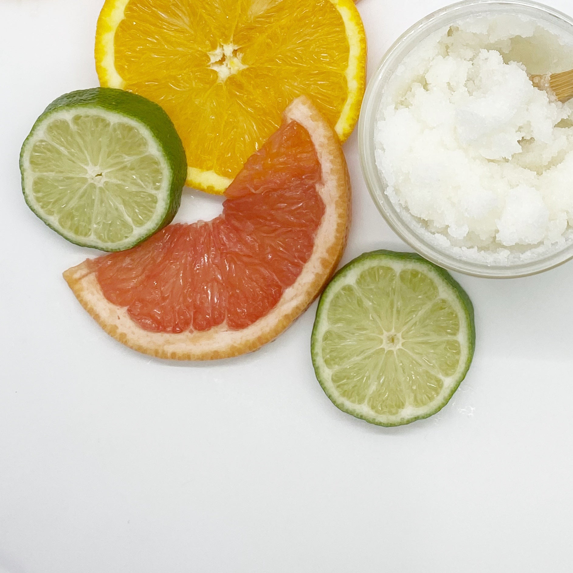 Close-up of Citrus Herb Sugar Scrub texture, surrounded by orange, lime, and grapefruit slices – exfoliating and moisturizing body scrub