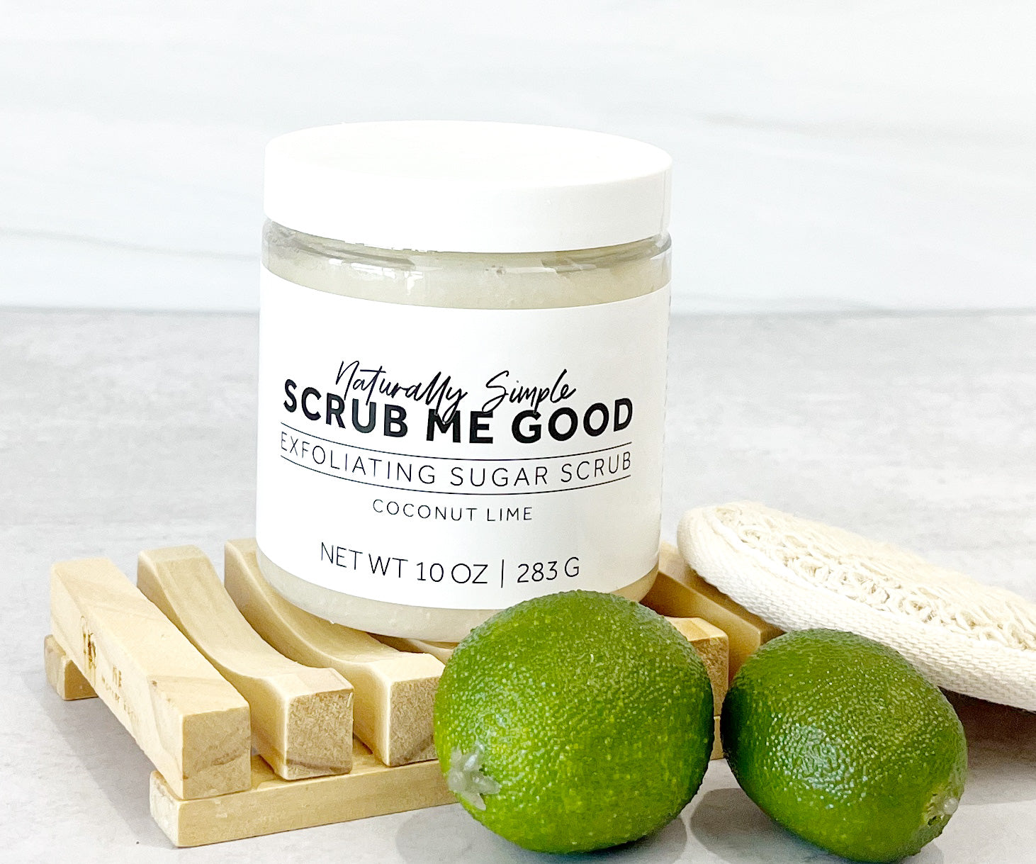 Tropical coconut lime body scrub for dry skin surrounded by limes