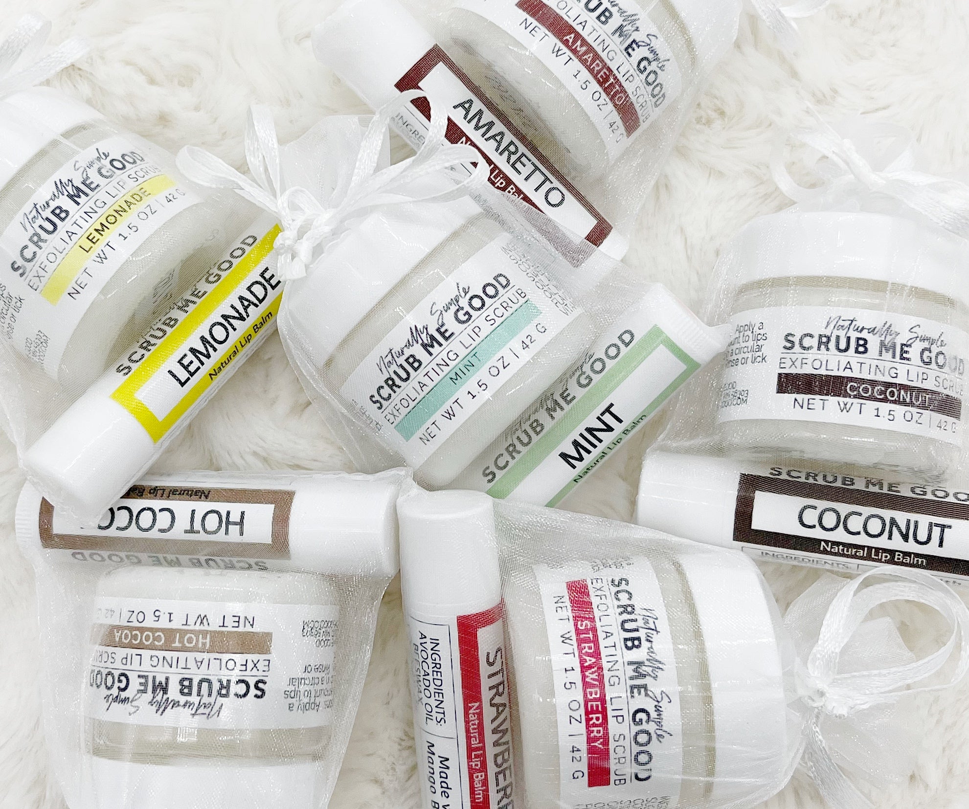 Lip scrub and balm bundles scattered on a white fluffy blanket