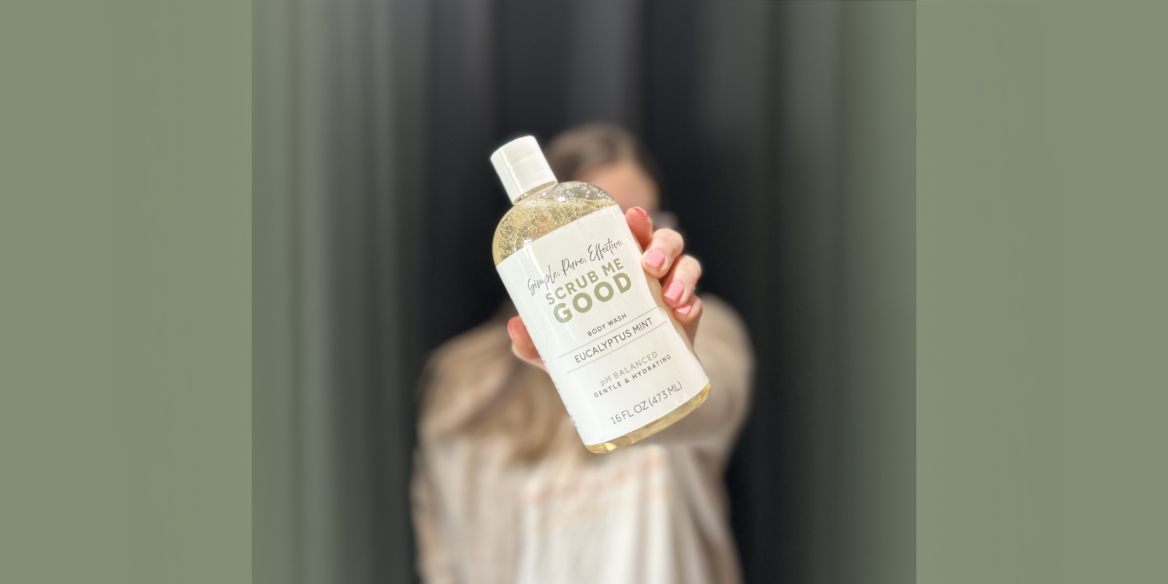 woman ohlding out a bottle of scrub me good ph balanced intimate safe body wash out infront of her