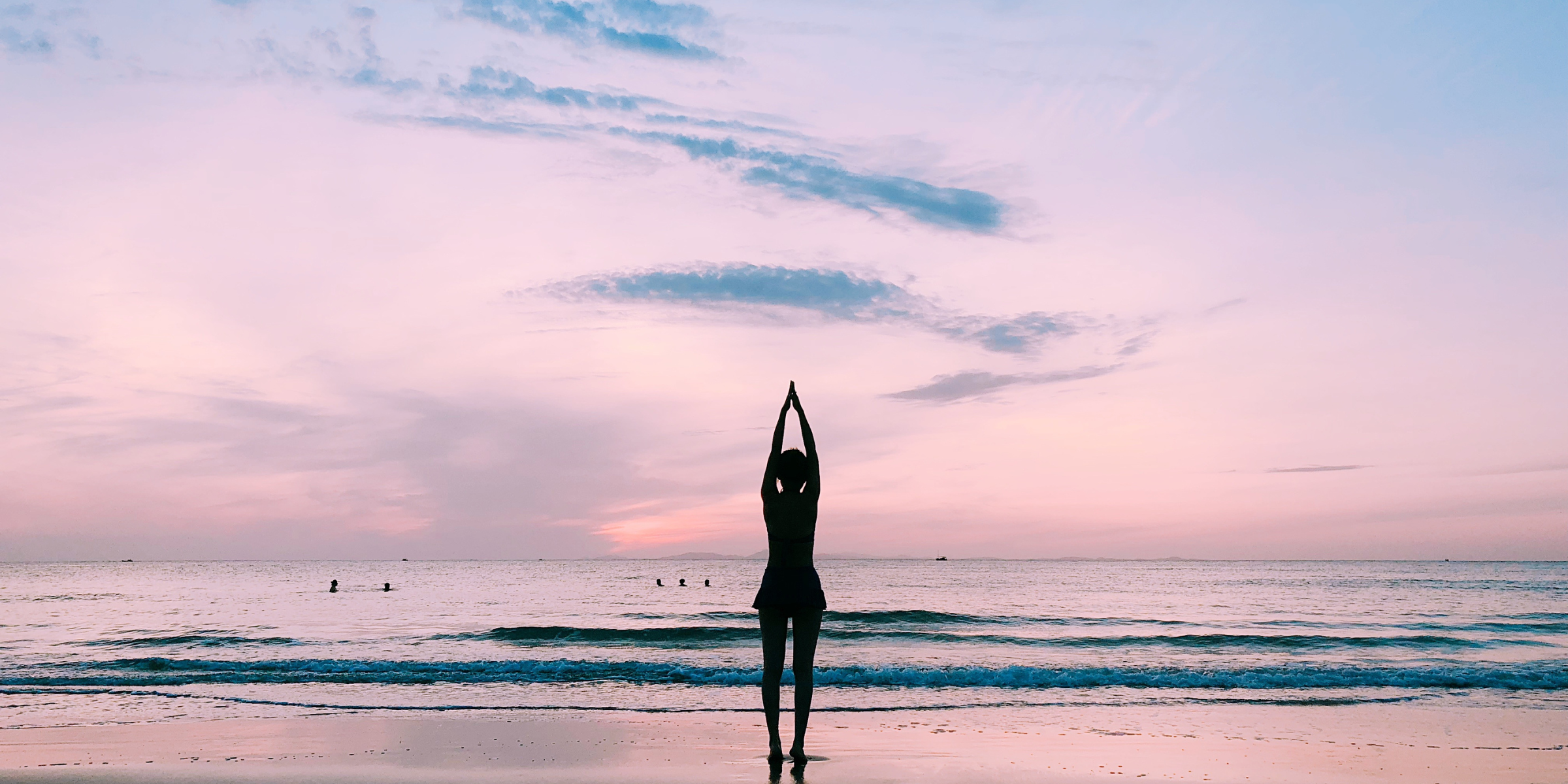 woman doing yoga on a beach in front of a sun rise or sun set