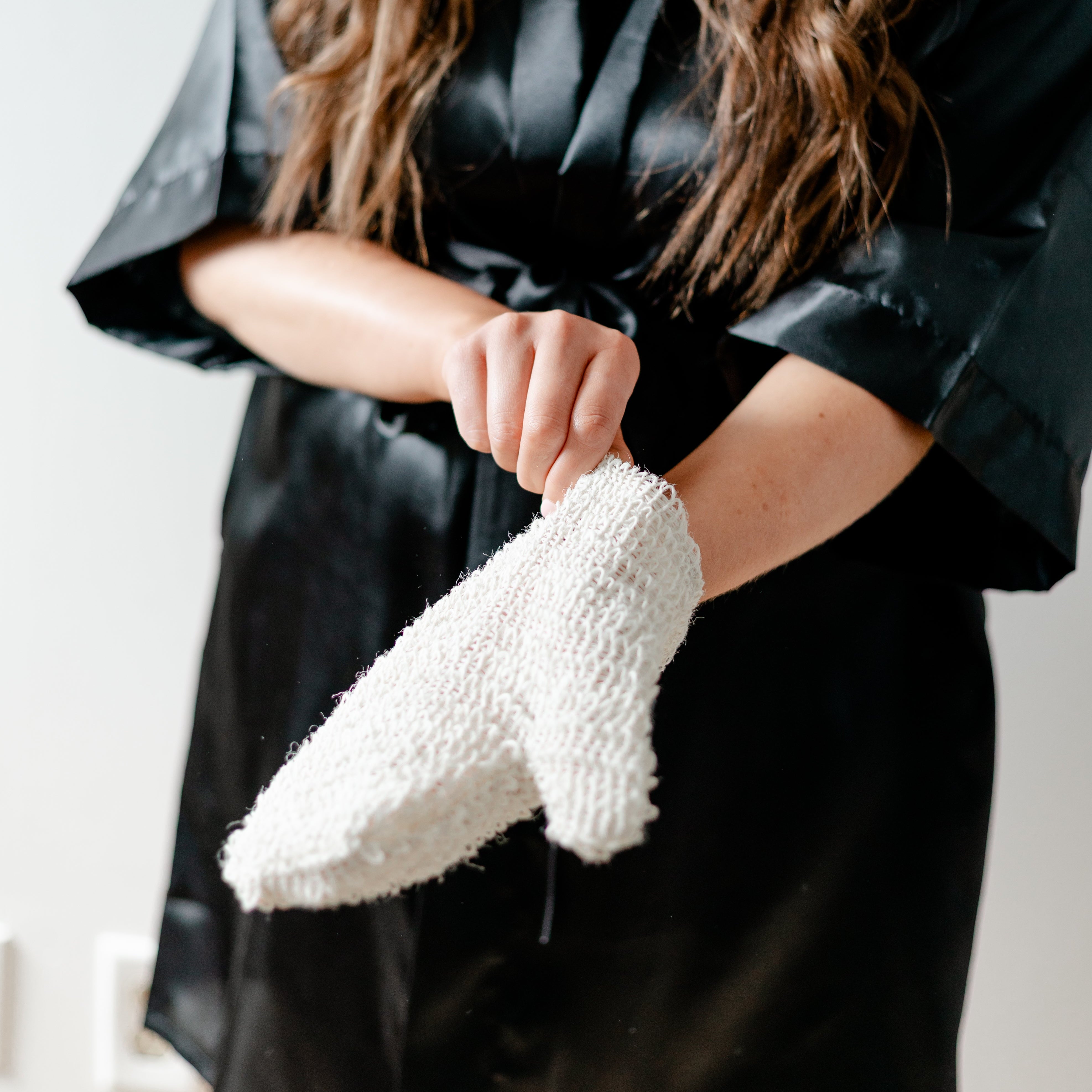 woman putting exfoliating mitt on hand