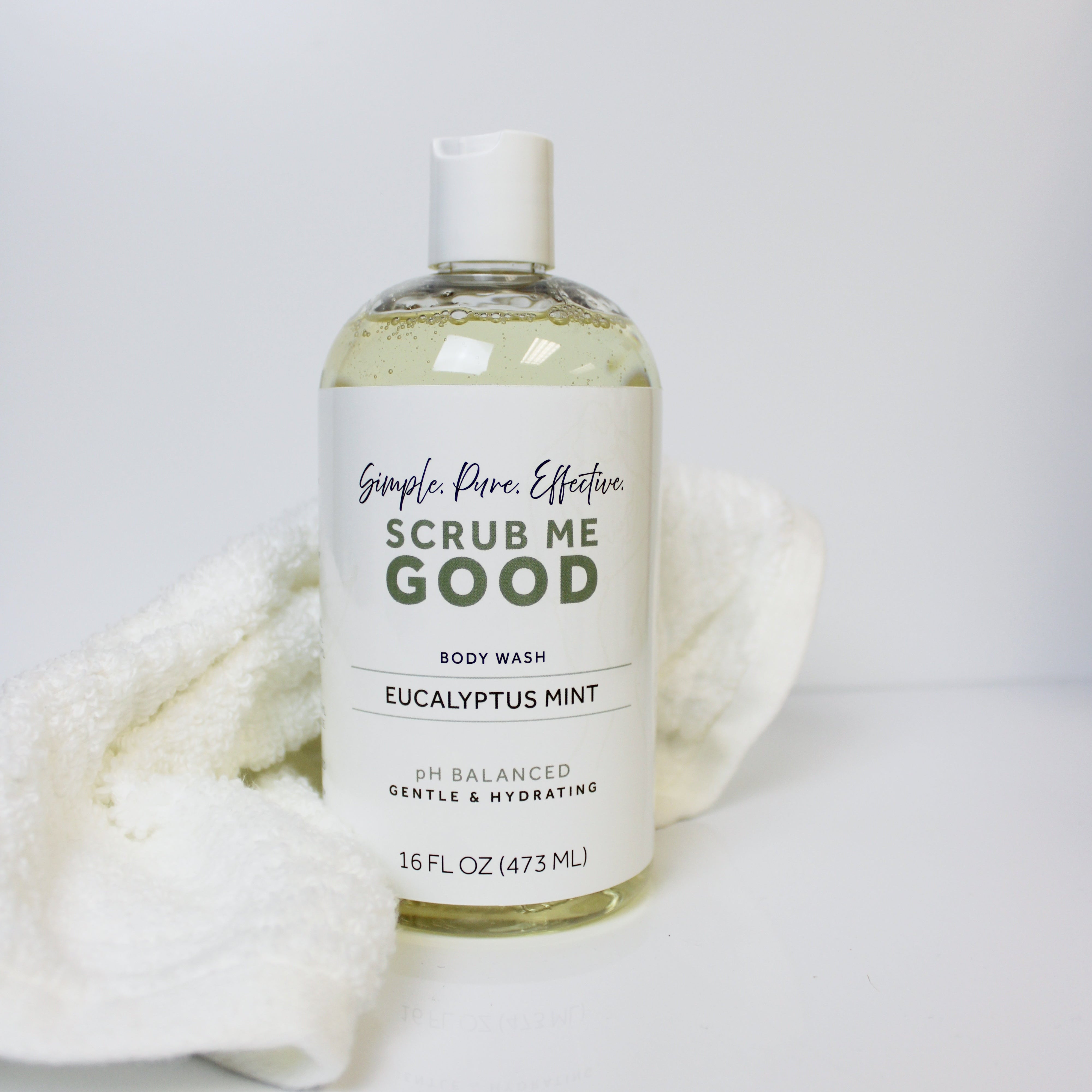 Bottle of Scrub Me Good body wash with a white label on a light gray background