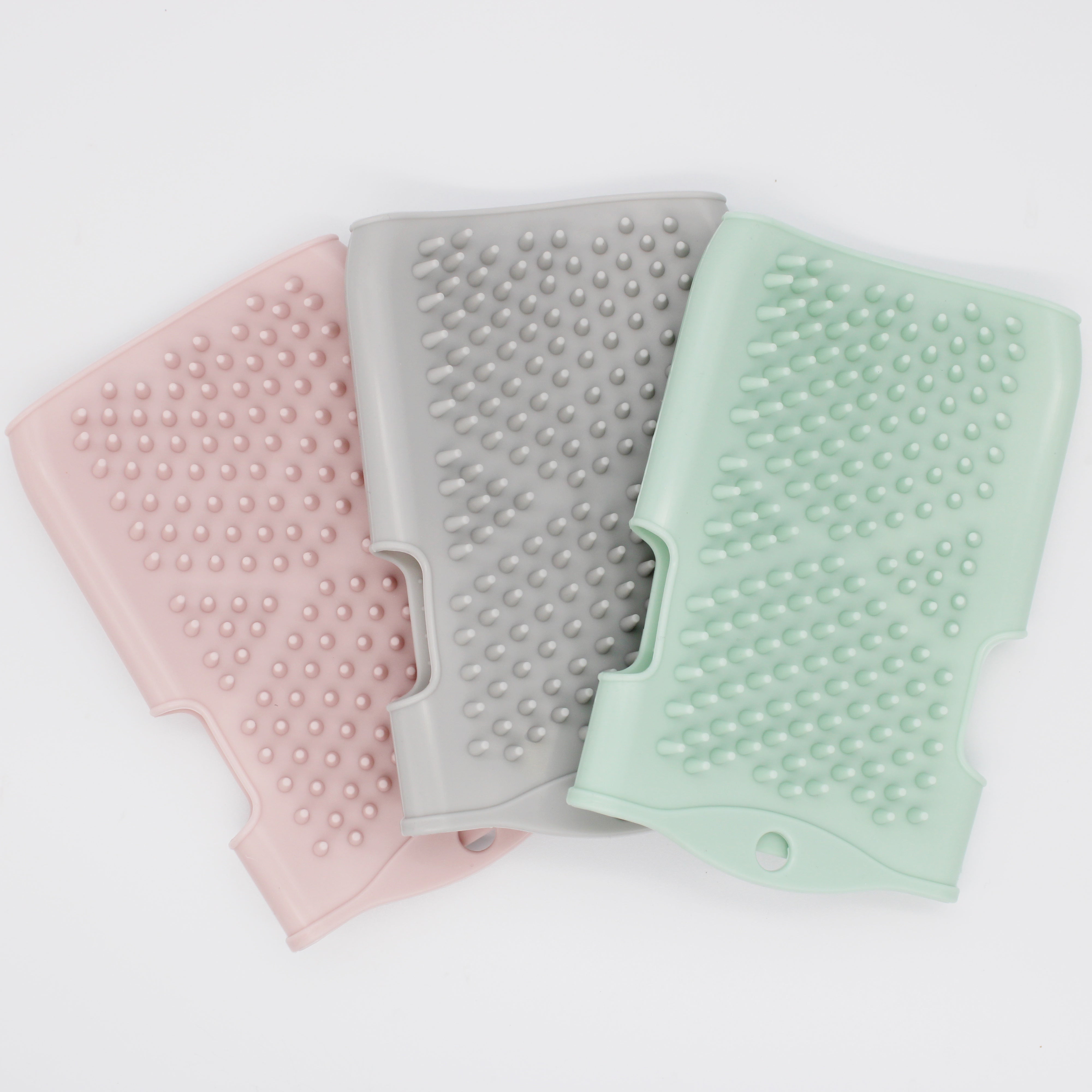 Three silicone gloves in pink, gray, and green on a white background
